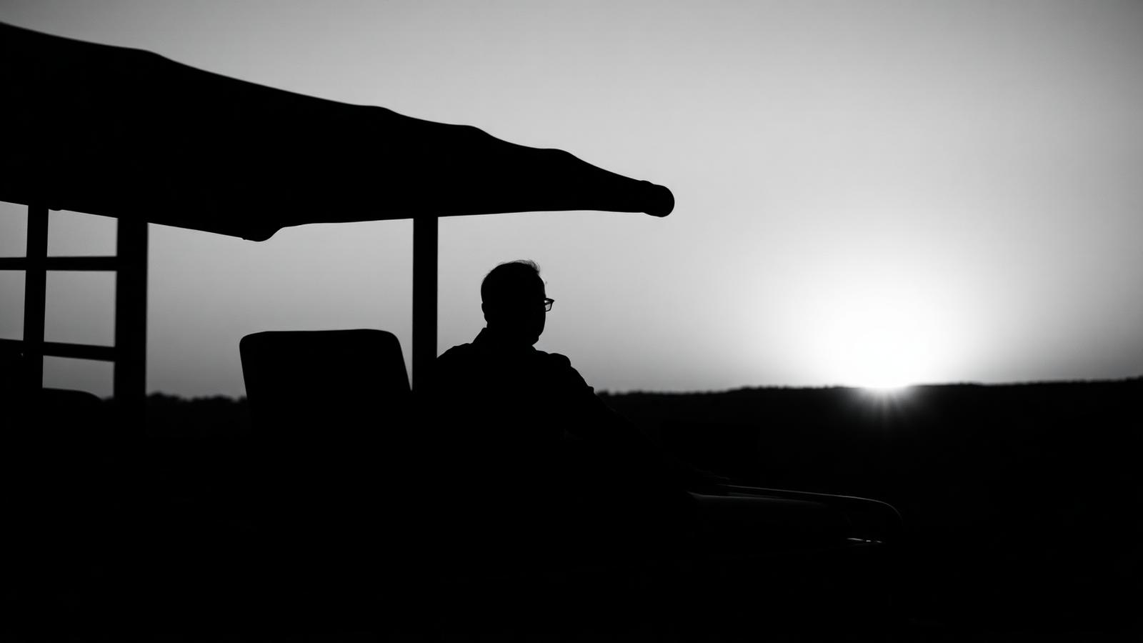 Safari guide beside a 4x4 at sunset